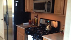 A kitchen with wooden cabinets, a stainless steel refrigerator, a microwave, a stove, and a kettle. - BEAUTIFUL MTN VIEW , HOT TUB & NEAR GOLF (Laveen)