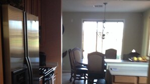 A kitchen with a refrigerator, stove, and dining area with chairs and a table. - BEAUTIFUL MTN VIEW , HOT TUB & NEAR GOLF (Laveen)