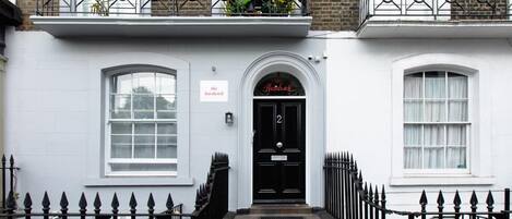 Un edificio blanco con una puerta negra que dice "The Hardwick".