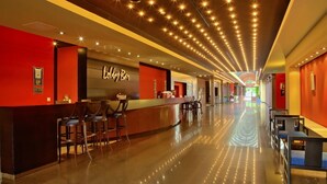 Un hall de hotel con recepción, zona de bar y asientos.