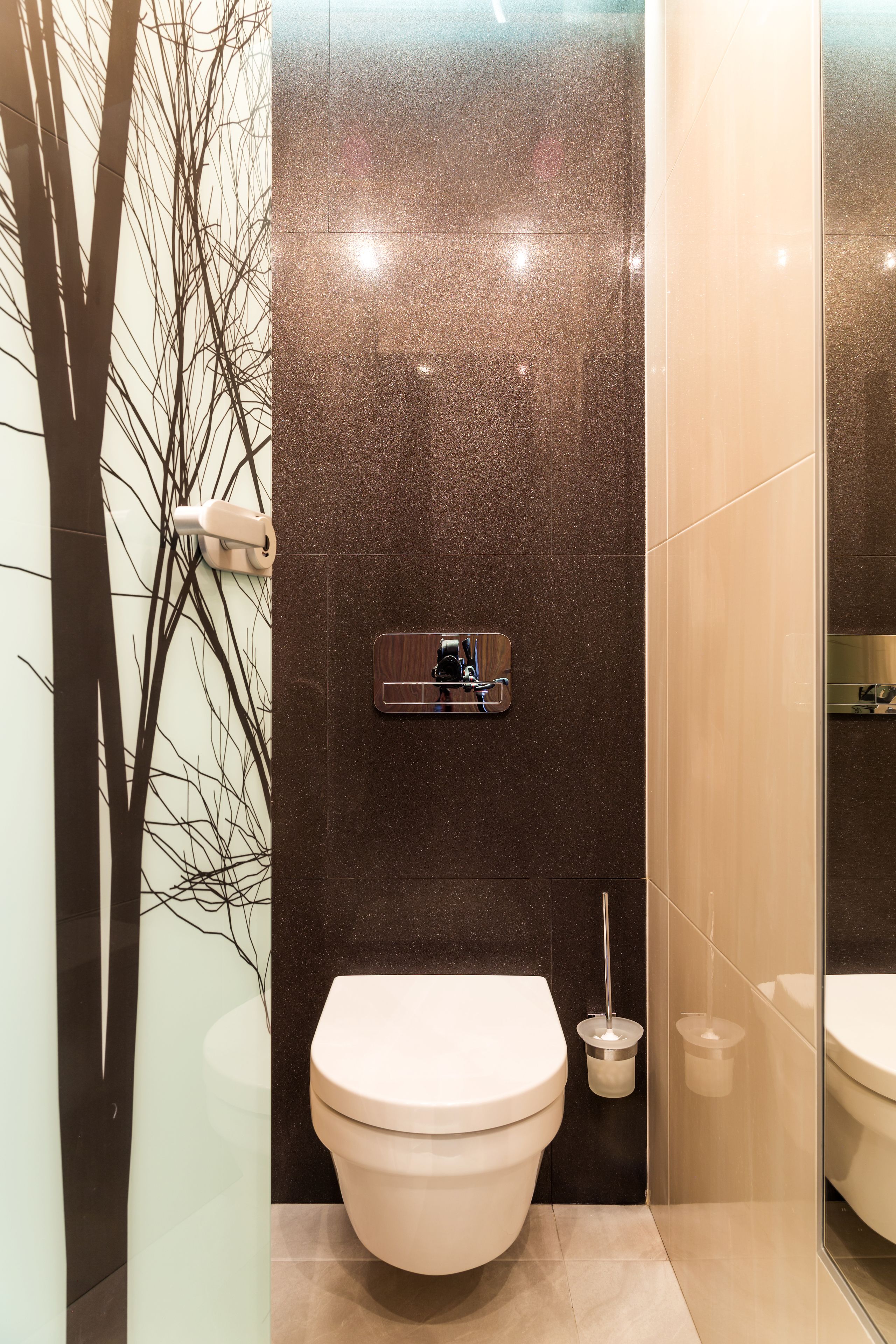 A modern bathroom with a toilet, a wall-mounted sink, and a glass shower enclosure.
