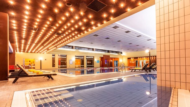 Una piscina interior con suelo de baldosas, un vestuario y una zona de recepción.