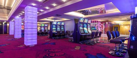 A casino floor with slot machines, gaming tables, and a vibrant butterfly carpet.