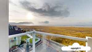Un balcon avec vue sur une plage et des montagnes lointaines.