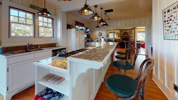 A spacious kitchen with a central island, wooden chairs, and pendant lighting. - OCEAN VIEW: SAND HILL MANOR:  Seaside Vacation Homes, Inc. Managed (Gearhart)