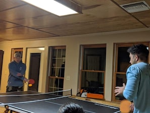 A ping pong table in a room with wooden walls and large windows.