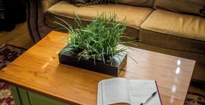 A wooden coffee table with a potted plant and an open notebook with a pen.