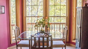 Un espace repas comprenant une table, des chaises, un ventilateur de plafond et de grandes fenêtres.