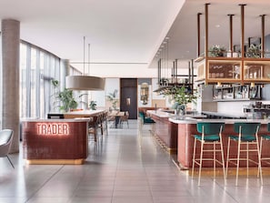 Zona de bar moderna con mostrador identificado como 'TRADER', asientos y vista del área de bar.