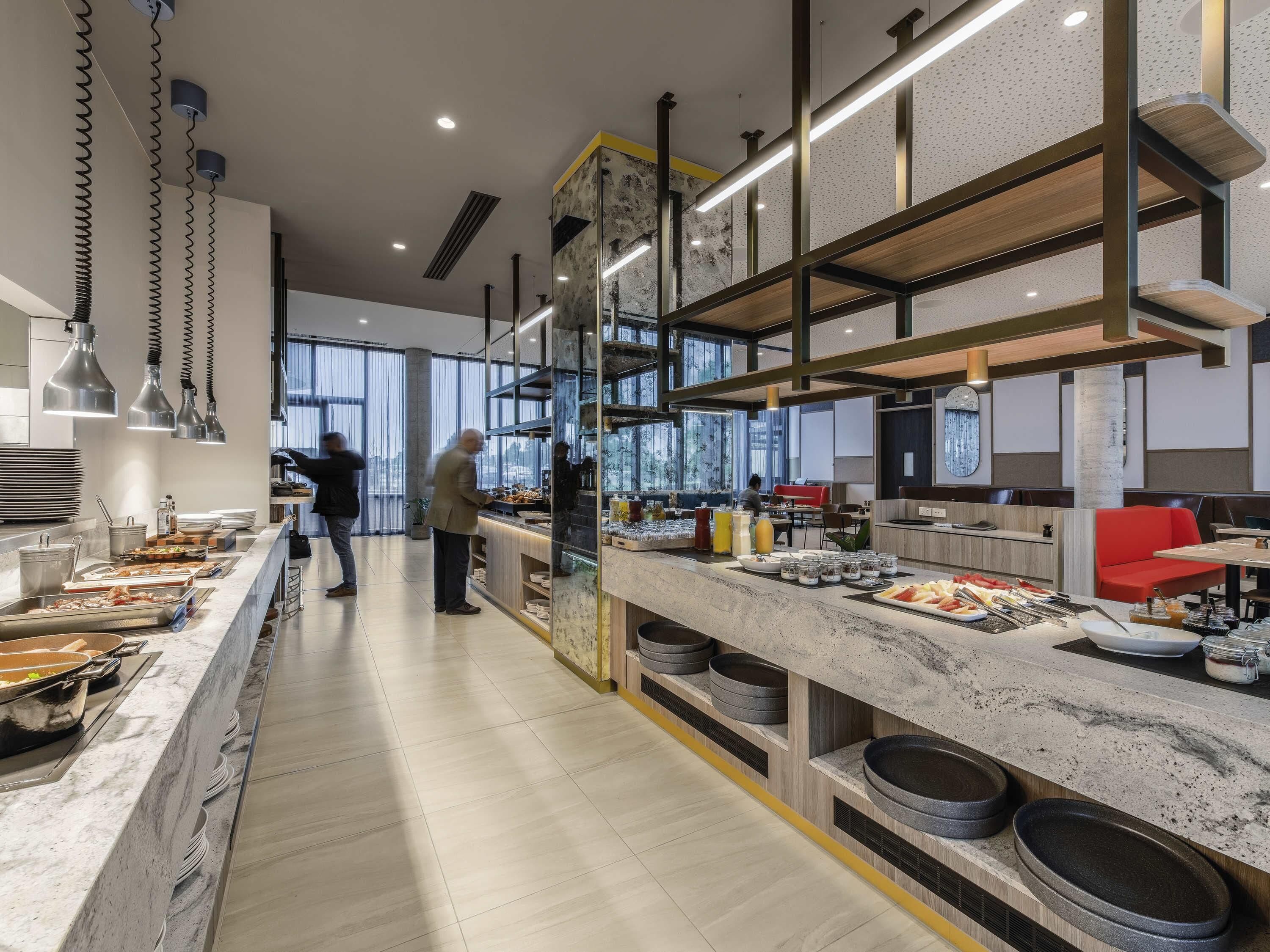 Una cocina moderna con una encimera larga, luces colgantes y vistas a la ciudad.