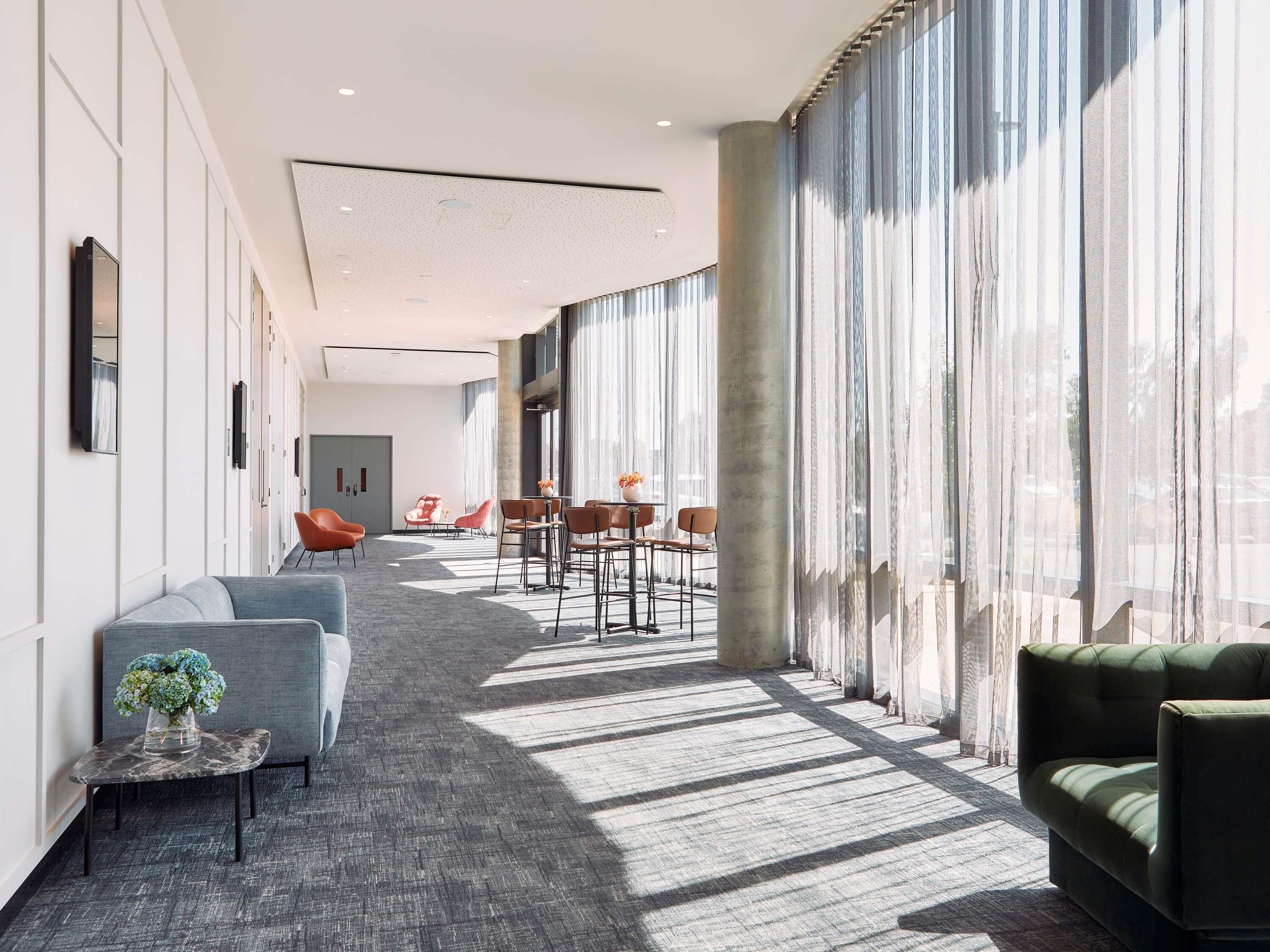 En moderne hotellobby med en lang gang, siddepladser og store vinduer.