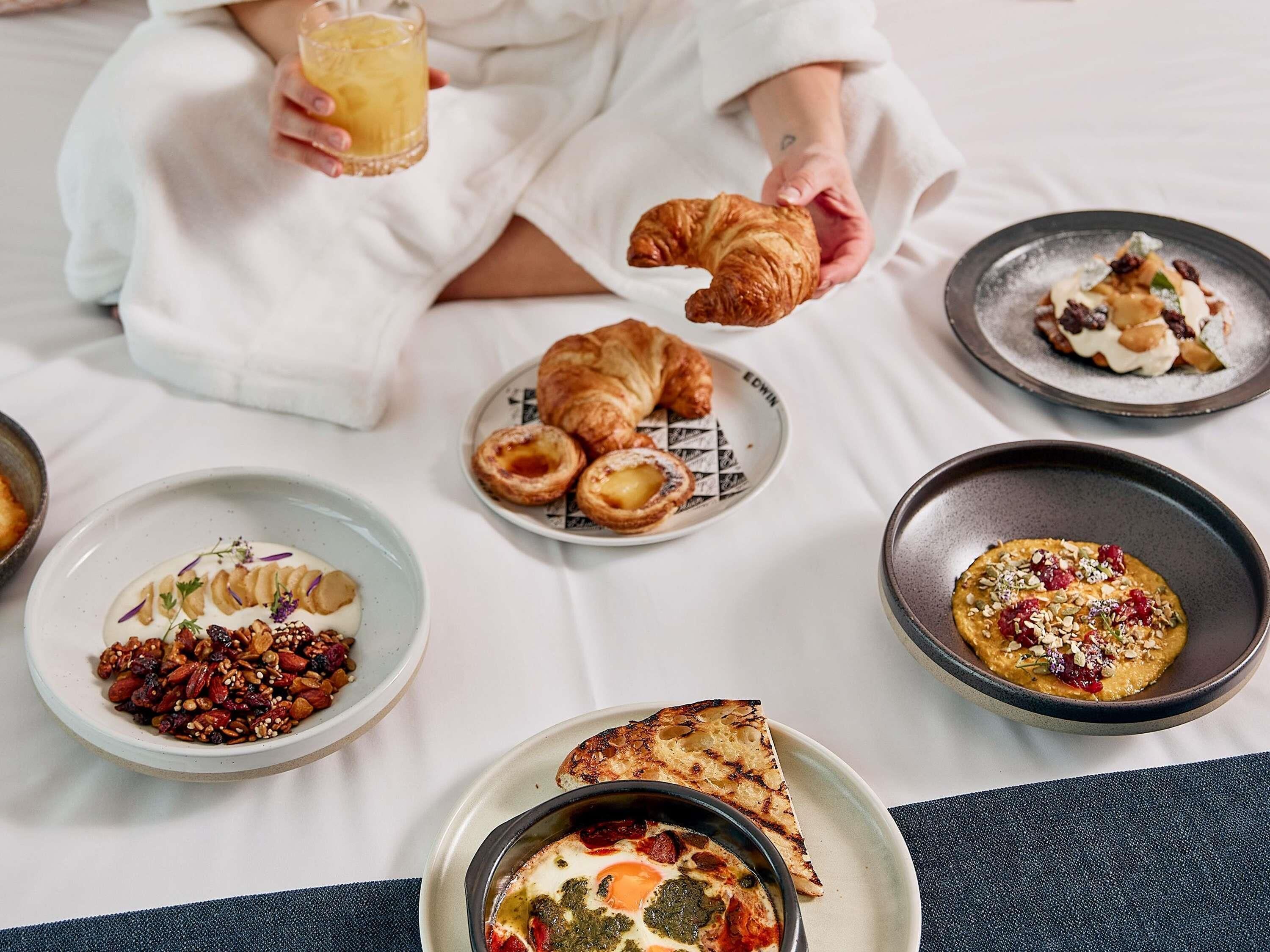 A breakfast setting with croissants, pastries, and a variety of dishes on a table.