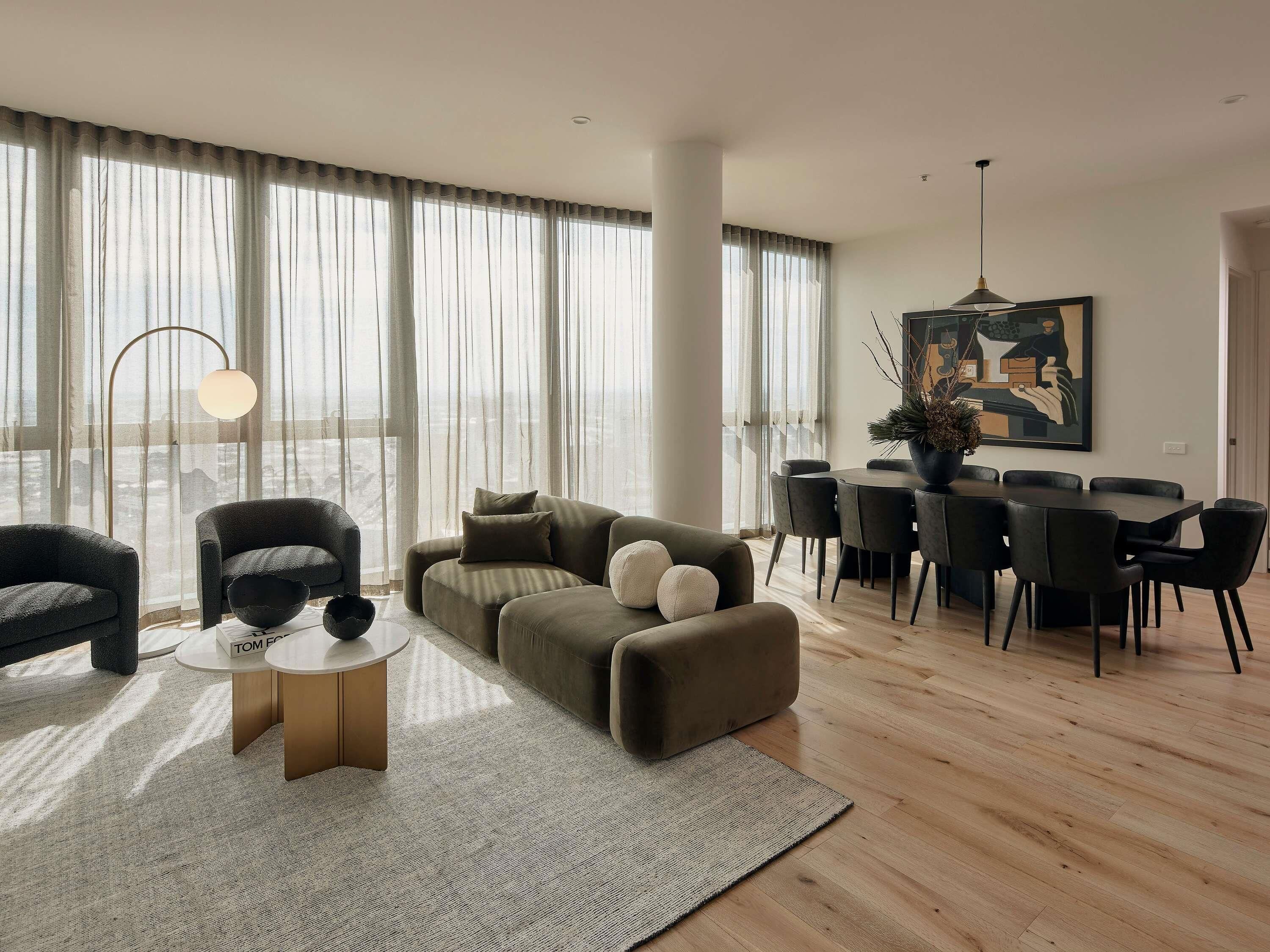 A modern living room with a sectional sofa, a round coffee table, and a dining area with a table and chairs.