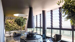 Zona lounge moderna con un elemento centrale a camino, posti a sedere e ampie finestre con vista.