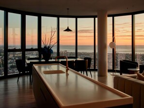 A modern interior with large windows, a dining area, and a view of the cityscape. - Shadow Play by Peppers (Southbank)