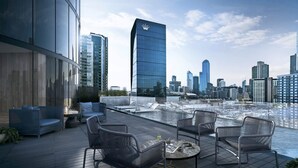 Una terrazza sul tetto con arredi moderni, una piscina e vista sullo skyline cittadino.