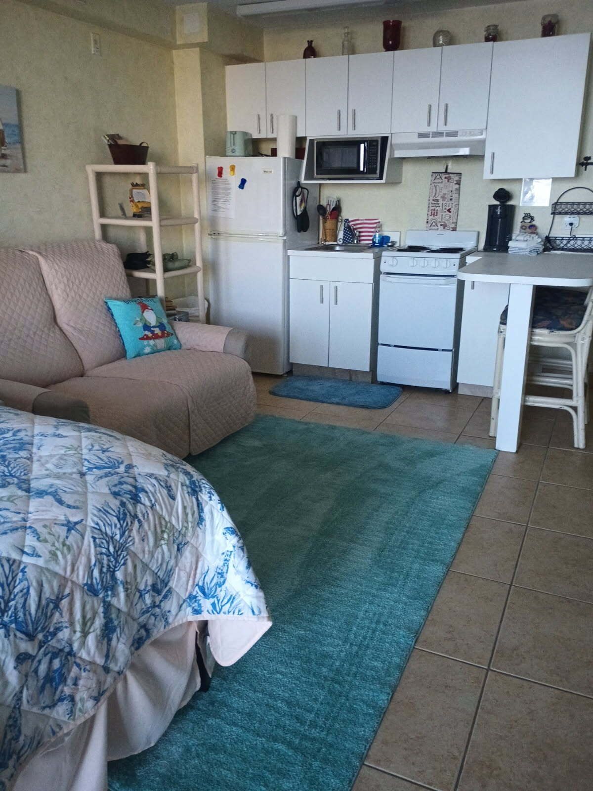 A compact living space with a kitchenette, a sofa, a bed, and a small dining area.