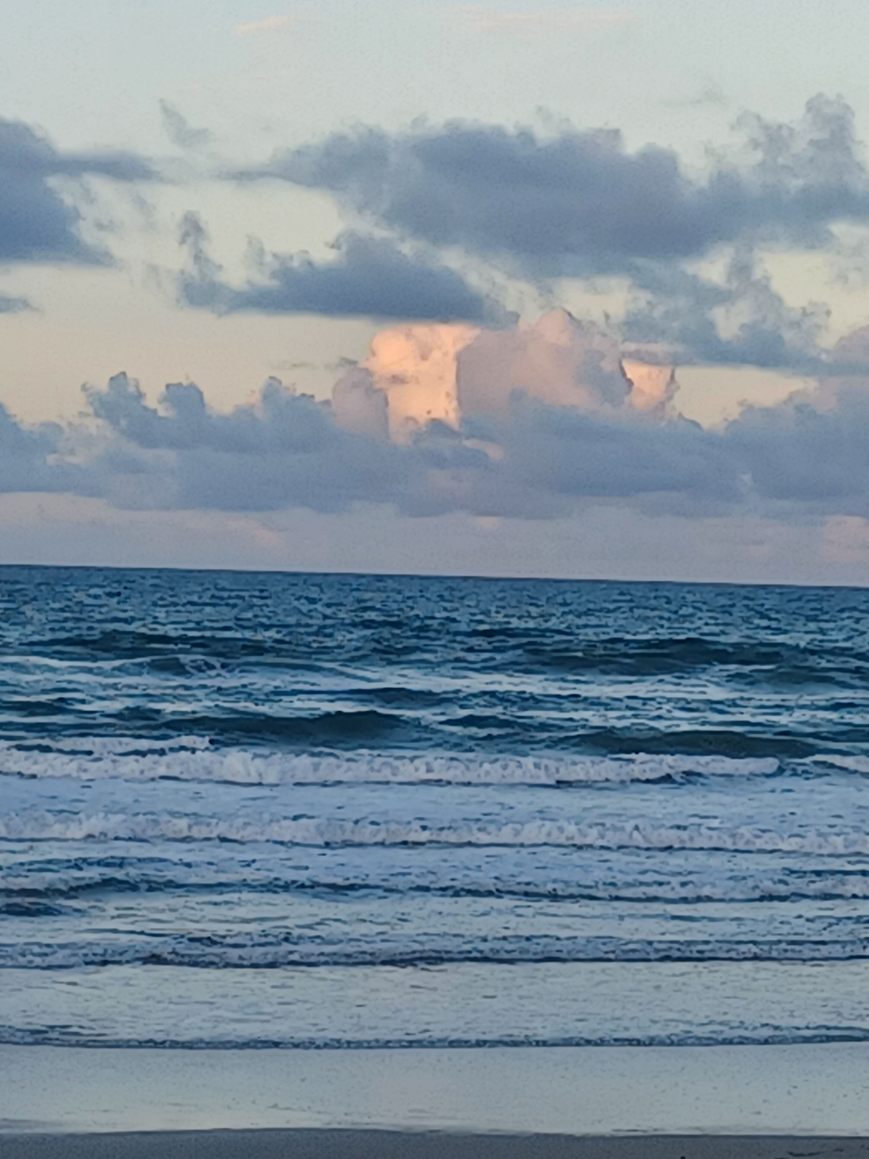 Une plage avec des vagues et un ciel nuageux.