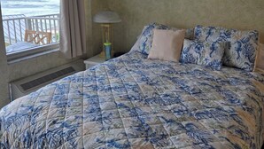 A bedroom with a large bed, a window with a view of the ocean, a small table with a lamp, and a wall sign that says 'LIVE LAUGH LOVE'. - Gorgeous Ocean View & Heated Pool! Seasonal Discounts (Daytona Beach)