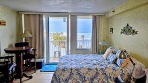 A hotel room with a bed, a desk, a chair, a lamp, and a view of the ocean. - Gorgeous Ocean View & Heated Pool! Seasonal Discounts (Daytona Beach)