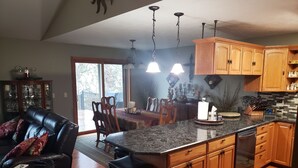 Una cocina amplia con armarios de madera, encimera de granito y comedor con sofá y sillas de cuero.