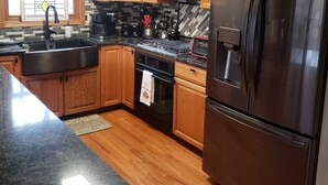Una cocina con armarios de madera, un refrigerador de acero inoxidable, un microondas, una estufa y un lavamanos.