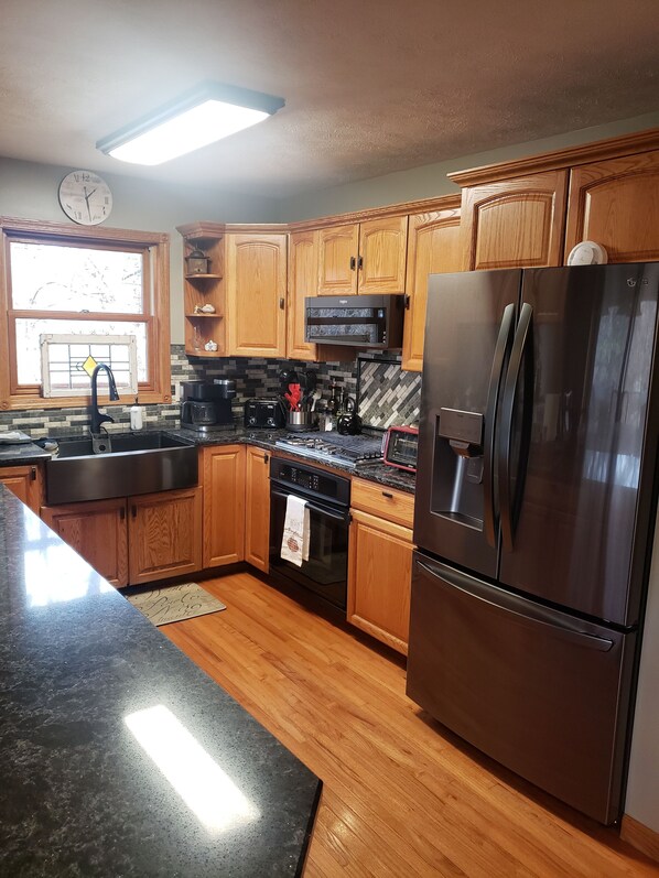 A kitchen with wooden cabinets, a stainless steel refrigerator, a microwave, a stove, and a sink. - Perfect family getaway! Beautiful Lakes, beaches, Marina and golf. Best in N MI. (Elk Rapids)