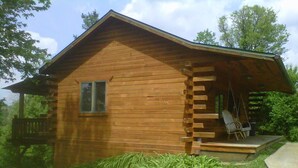 Una cabaña de madera con porche, ventana y una pequeña terraza.