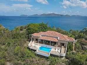A coastal villa with a swimming pool, terracotta roof, and ocean views.