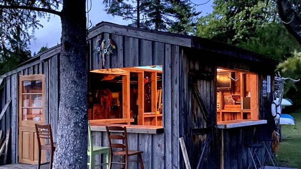 A rustic wooden cabin with a porch, a dining area, and a bar.