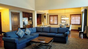 A living room with a sectional sofa, a coffee table, and a dining area with a table and chairs.