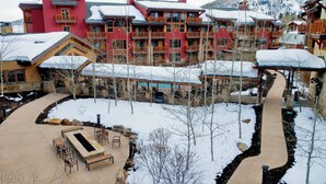 A snow-covered courtyard with outdoor seating, a pool, and a building with multiple balconies.