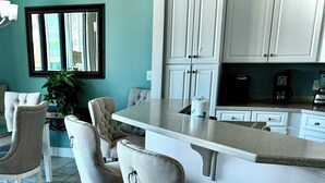 A kitchen with white cabinets, a bar area with stools, and a tiled floor. - Free boat slip w/ Luxury 2 BR /Water front, on Terry Cove Condo  (Orange Beach)