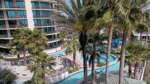 A multi-story hotel with a pool area surrounded by palm trees. - Free boat slip w/ Luxury 2 BR /Water front, on Terry Cove Condo  (Orange Beach)
