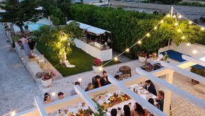 Recepción de boda al aire libre con mesas dispuestas bajo toldos blancos, rodeada de follaje e iluminada con guirnaldas de luces.
