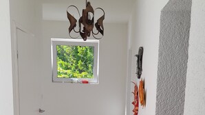 A hallway with a tiled floor, a window with a view of greenery, a ceiling fan, and a door. - Rustic House Miketa -family- friendly holiday home for nature lovers! (Lukoran)