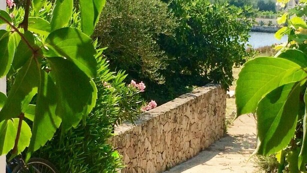 A pathway lined with greenery and a stone wall, leading to a body of water. - Rustic House Miketa -family- friendly holiday home for nature lovers! (Lukoran)