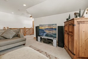 A living room with a sofa, a television on a stand, a wooden cabinet, and a ceiling fan. - Bear mountain resort 5bd 3 bath sleeps 2600 sq (Big Bear Lake)