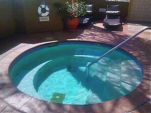 A small, round swimming pool with a metal ladder, surrounded by a tiled deck.