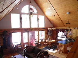 Cozy cabin interior with a high ceiling, dark sofa, and dining table for four.