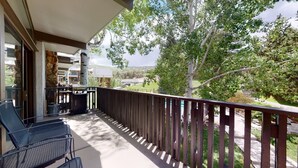 A balcony with outdoor seating, a stone pillar, and a view of a residential area.