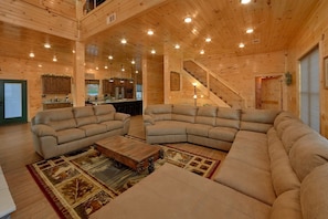 A spacious living area with a large L-shaped sectional sofa, a wooden coffee table, and a patterned rug.