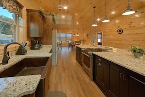 A kitchen with wooden walls, granite countertops, and stainless steel appliances.