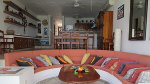 A living room with a curved sectional sofa, a wooden coffee table, and a tiled floor. - Breathtaking 7 Bedroom Villa on the Ocean with a Infinity Private Pool (Isla Mujeres)