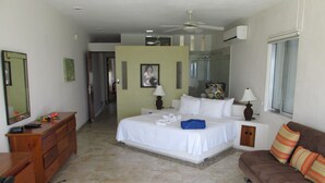 A hotel bedroom with a bed, a dresser, a sofa, and a shower area. - Breathtaking 7 Bedroom Villa on the Ocean with a Infinity Private Pool (Isla Mujeres)