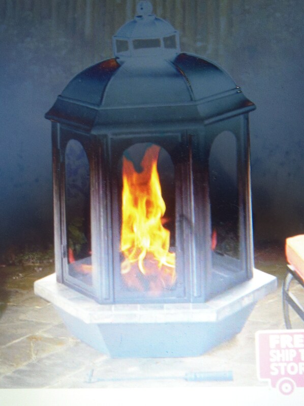 A glass lantern with a fire inside, placed on a white stand.