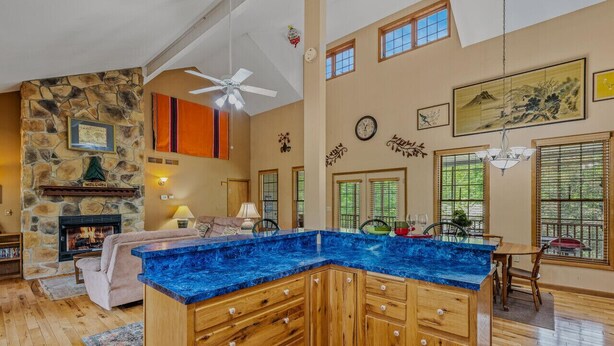 A spacious kitchen with a blue marble countertop, wooden cabinets, and a stone accent wall. - Blue Badger Cottage-wifi, screen porch, fire pit, game room, king bed, fireplace (Berkeley Springs)