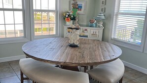 Une table de salle à manger ronde en bois, avec des bancs rembourrés, un lustre et une enseigne au-dessus indiquant : « Island Time Tiki Bar ».