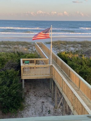 A wooden boardwalk leading to a beach with an American flag on a flagpole. - 'Stress Free By The Sea'
(Topsail Beach)