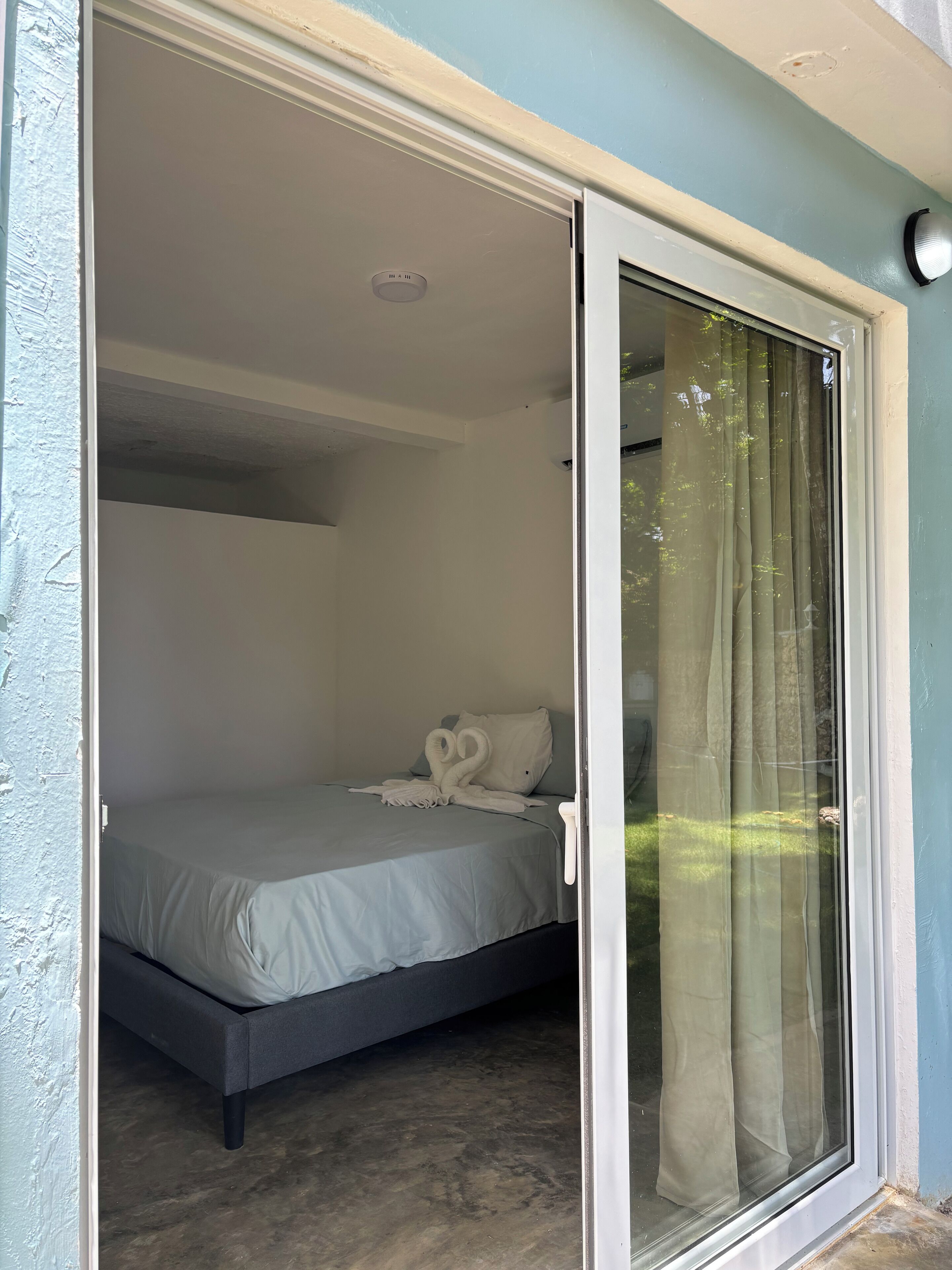 A room with a bed, a ceiling light, and a sliding glass door.